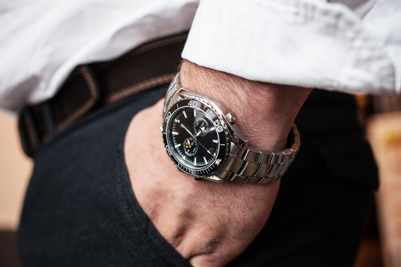 close-up men's wrist watch in white shirt hand in black trousers pocket article about men's style or luxury watches lifestyle of a winner.